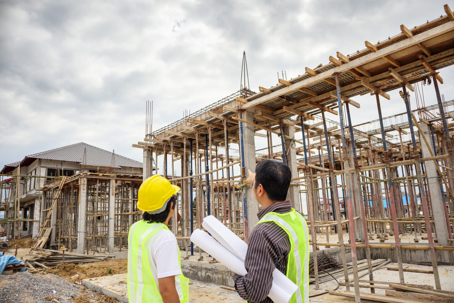 Asian business man construction manager and engineer worker in protective helmet hold blueprints paper on hand at house building site